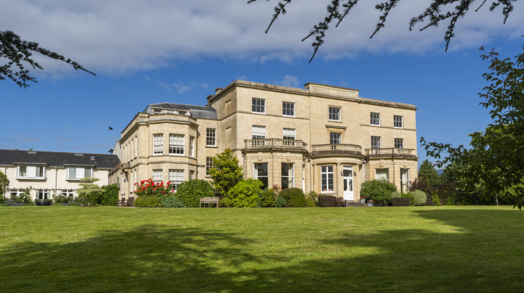 The Georgian exterior of Penny Brohn UK set in green gardens under a bright sky